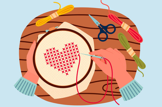An illustration of one hand holding embroidery hoop and another hand holding a needle with thread showing cross stitching.