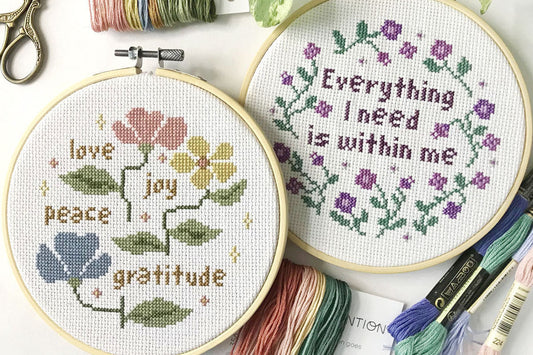 photograph of finished cross stitch in embroidery hoop. one is saying "Everything i need is within me" and another one saying "love, joy, peace, gratitude."