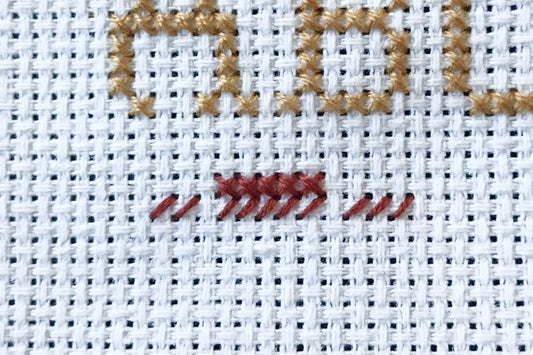 Close up of cross stitch showing half stitches before finishing them into full stitches
