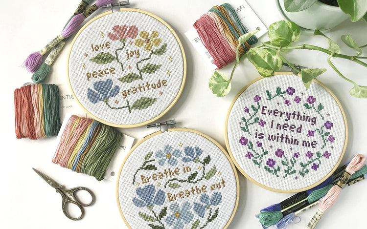 A flat lay of three finished cross stitch projects. A beautiful reminder of mindfulness, self-care, and intentional living.